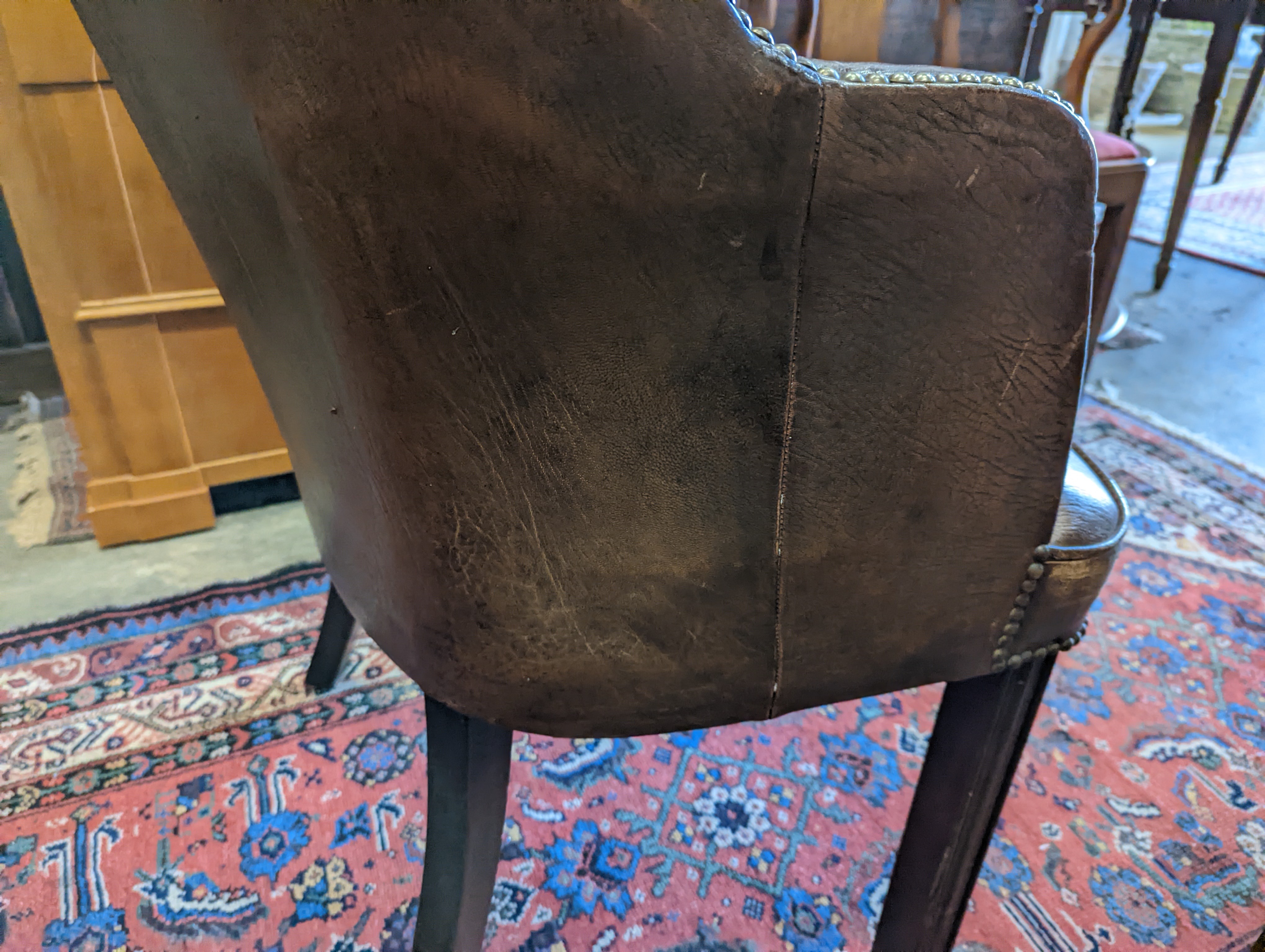 A brown leather upholstered desk chair, a mahogany hall chair and two upholstered armchairs